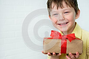 portrait of a boy 4-5 years old in a yellow shirt with a gift in his hands. The child is smiling, happy. Received a gift
