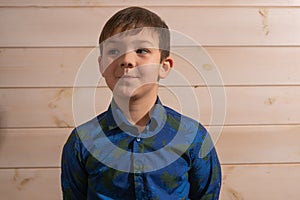 Portrait of a boy 8 years old brunette in a blue shirt. Smiling with closed lips