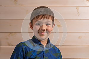 Portrait of a boy 8 years old brunette in a blue shirt. Smiling with closed lips