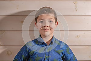 Portrait of a boy 8 years old brunette in a blue shirt. Smiling with closed lips.