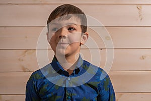 Portrait of a boy 8 years old brunette in a blue shirt. Smiling with closed lips.