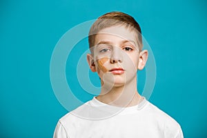 Portrait of a boy with adhesive plaster on his cheek