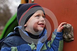 Portrait of boy in blue jacket by the climbing wall