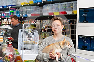 Portrait of a boy with dog in petshop, man on background