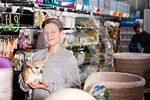 Portrait of a boy with dog in petshop, man on background