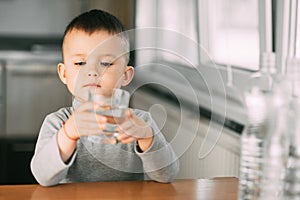 Portrait of a boy drinking a glass of water,happy in the kitchen