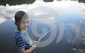 Portrait of a boy fishing in lake reflecting the sky