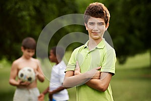 Portrait of boy and friends playing football in park
