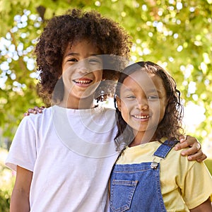 Portrait Of Boy And Girl Standing In Garden Smiling At Camera