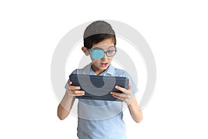 Portrait of boy in glasses with patch for glasses. Boy with tablet. Treat lazy eye, amblyopia, strabismus.  Remote learning. Dista