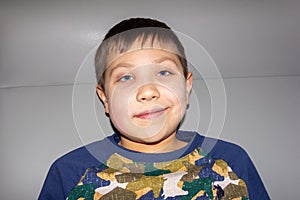 portrait of a boy with a grin on his face on a gray background.