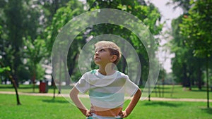 Portrait of boy looking around lawn close up. Cheerful child standing on meadow.