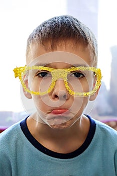 Portrait of a boy making faces in funny yellow glasses made on a 3d printer