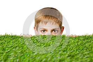 Portrait of a boy peeping out through grass