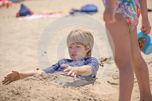 Portrait of a boy playing on the beach buried in the sand