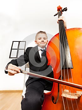 Portrait of boy playing cello sitting on the chair