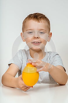 Portrait boy posing isolated holding large citrus fruits looking at camera with happy joyful facial expression