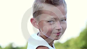 Portrait, a boy of seven, in a white T-shirt. Cheerful, happy family vacation. Outdoors, in the summer, near the forest