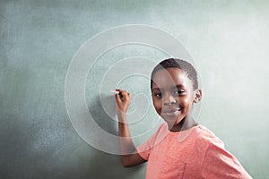 Portrait of boy standing by chalkboard photo