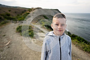 Portrait of a boy standing on the edge of a cliff near sea