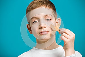 Portrait of a boy tearing off adhesive plaster from his che