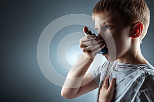 Portrait of a boy using an asthma inhaler to treat inflammatory diseases, shortness of breath. The concept of treatment for cough