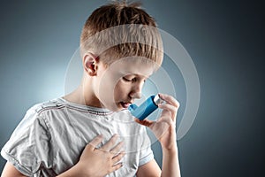 Portrait of a boy using an asthma inhaler to treat inflammatory diseases, shortness of breath. The concept of treatment for cough
