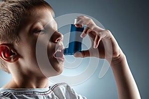 Portrait of a boy using an asthma inhaler to treat inflammatory diseases, shortness of breath. The concept of treatment for cough