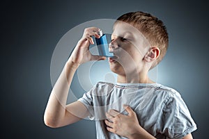 Portrait of a boy using an asthma inhaler to treat inflammatory diseases, shortness of breath. The concept of treatment for cough