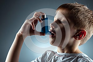 Portrait of a boy using an asthma inhaler to treat inflammatory diseases, shortness of breath. The concept of treatment for cough