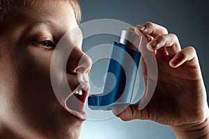 Portrait of a boy using an asthma inhaler to treat inflammatory diseases, shortness of breath. The concept of treatment for cough