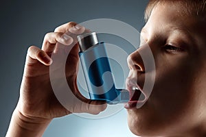 Portrait of a boy using an asthma inhaler to treat inflammatory diseases, shortness of breath. The concept of treatment for cough