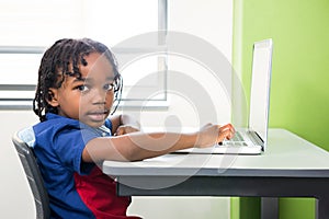 Portrait of boy using laptop in classroom