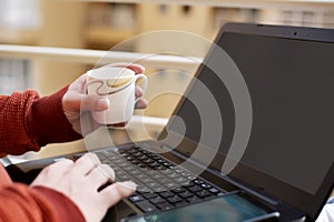 Portrait of boy is working on the laptop with holding tea cup in hand