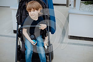 Portrait of boy 3 years old in baby carriage, looks at camera and smiles. childhood and carelessness photo
