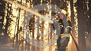 Portrait of a Brave Professional Firefighter Using a Firehose to Fight a Raging Dangerous Forest