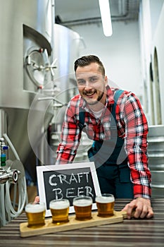 Portrait of brewer with four glasses of craft beer on table