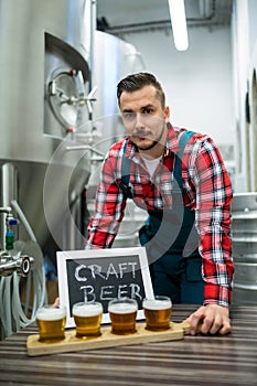 Portrait of brewer with four glasses of craft beer on table