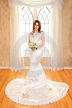 Portrait bride standing in front of window