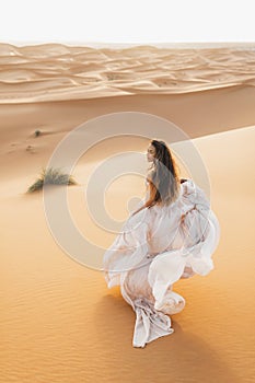 Portrait of bride woman in amazing wedding dress in Sahara desert dunes, Morocco