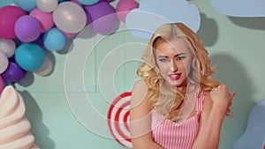 Portrait of a bright girl with blond hair on the background of colored balls.