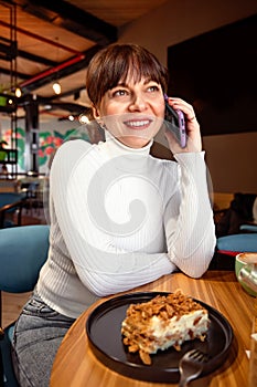 Portrait of a broadly laughing woman talking on the phone while sitting in a cafe photo