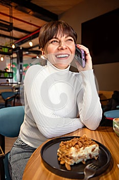 Portrait of a broadly laughing woman talking on the phone while sitting in a cafe photo