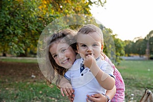 Portrait of brother and sister embracing in a park in the open air, concept of family love