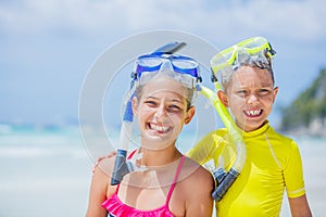 Portrait of Brother and sister in scuba masks playing on the beach during the hot summer vacation day.