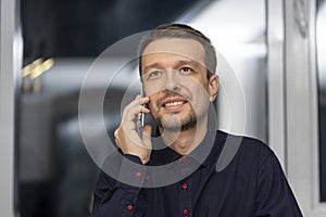 Portrait of a brunette 30-35 years old talking on a mobile phone in formal clothes, smiling on a neutral blurred background, close