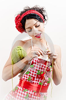 Portrait of brunette beautiful attractive woman pinup girl holding yarn and knits on white background