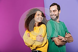 Portrait of brunette caucasian couple man and woman in colorful clothing smiling at each other standing with arms crossed