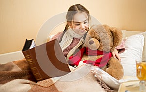 Portrait of brunette girl telling story to teddy bear at bed