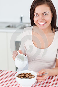 Portrait of a brunette pouring milk in her cereal